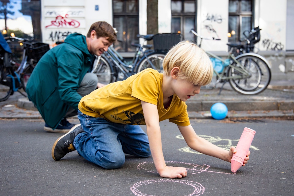 Temporäre Fahrräder auf der Straße: Der kleine Emil (6) und sein Papa Bodo P. (42) zeichnen mit Kreide auf dem Asphalt. 