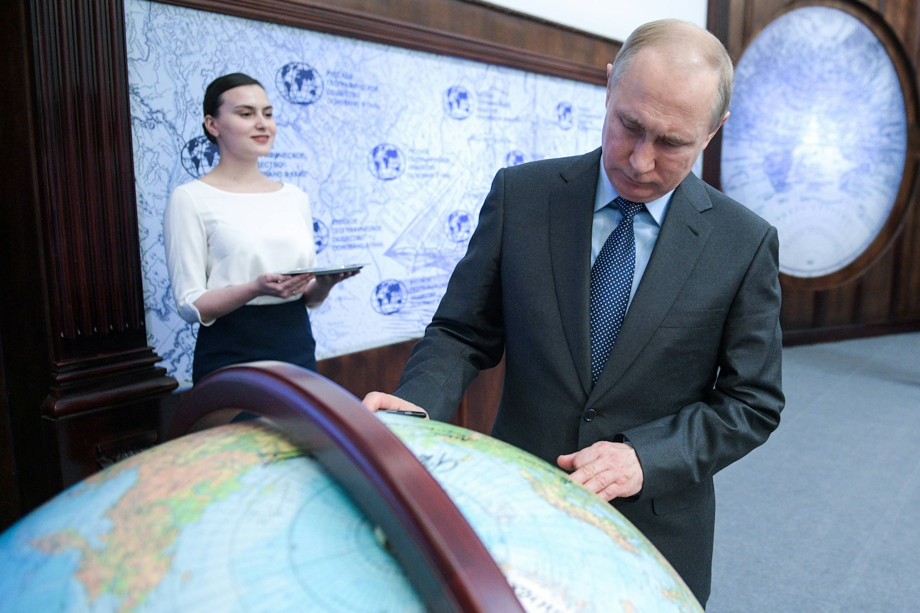O presidente russo Vladimir Putin assina um globo durante uma reunião do Conselho de Administração da Sociedade Geográfica Russa.