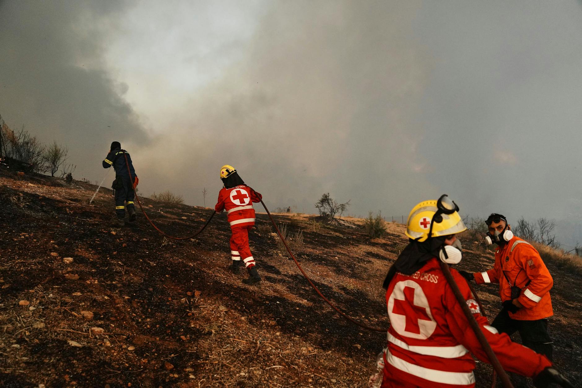 Griechenland, Patras: Ein Feuerwehrmann und Mitglieder des Roten Kreuzes versuchen, einen Waldbrand in der westgriechischen Stadt Patras unter Kontrolle zu bringen.