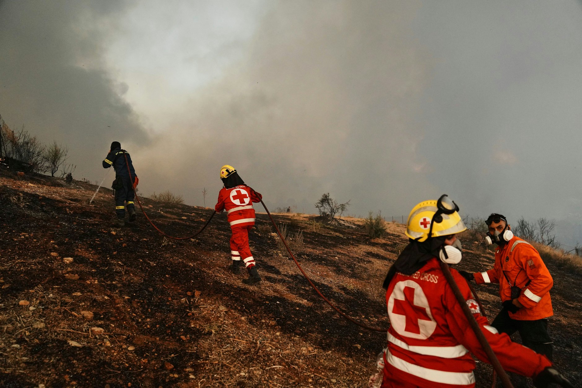 Griechenland, Patras: Ein Feuerwehrmann und Mitglieder des Roten Kreuzes versuchen, einen Waldbrand in der westgriechischen Stadt Patras unter Kontrolle zu bringen. 