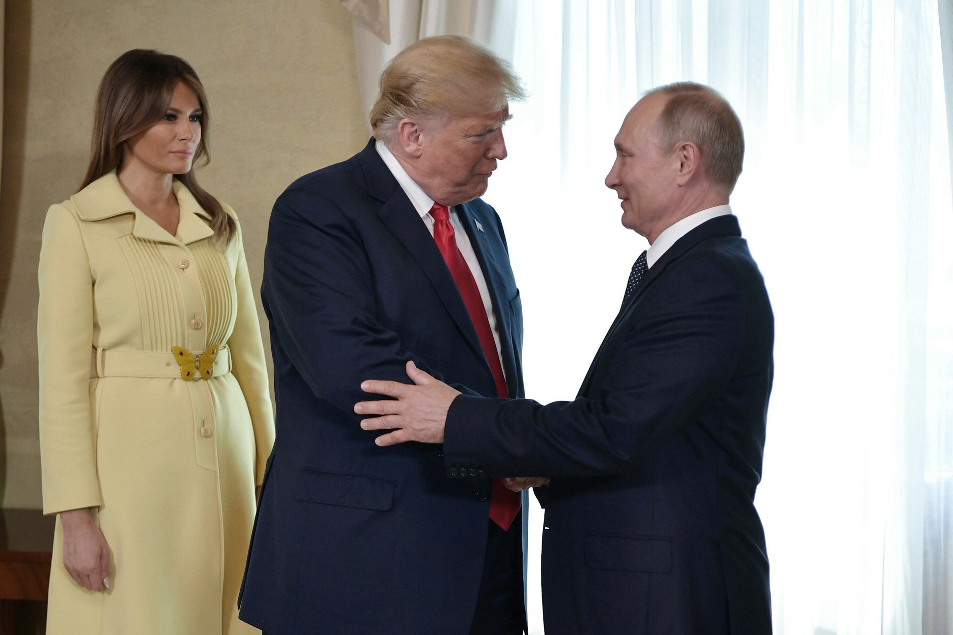 Finnland, Helsinki im Jahr 2018: US Präsident Donald Trump (M) und der russische Präsident Wladimir Putin (r) geben sich die Hand vor ihrem bilateralen Treffen, Melania Trump steht daneben.