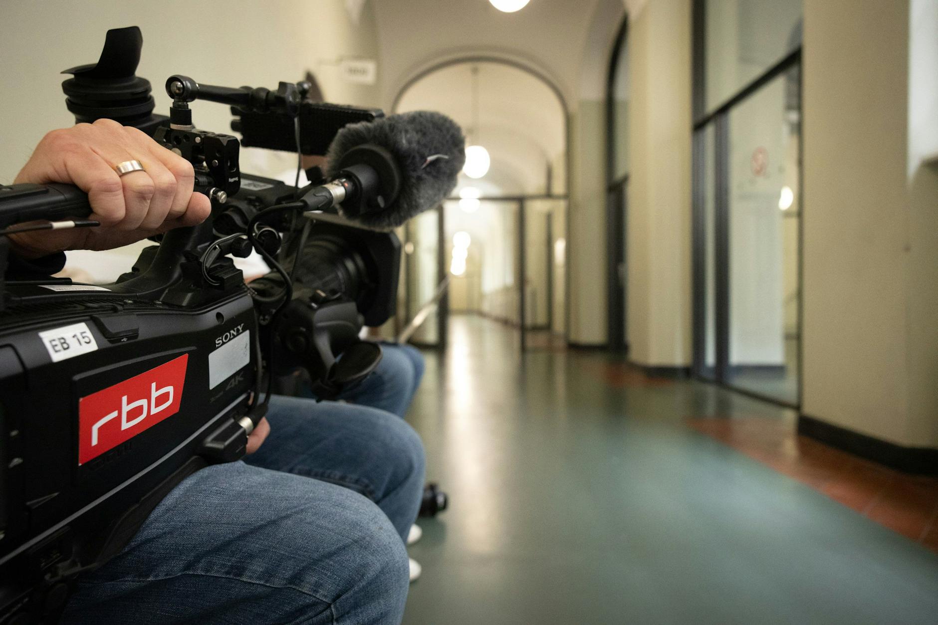 A cameraman waits in front of the courtroom door at the