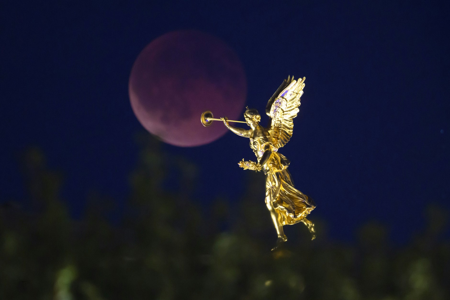 07.09.2025, Sachsen, Dresden: Der Mond geht am Abend zu einer totalen Mondfinsternis hinter dem Engel «Fama» auf der Kunstakademie auf.