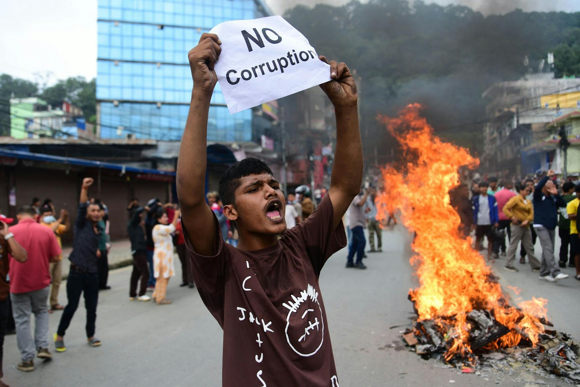 Ein Demonstrant in Nepal hält einen Zettel hoch, auf dem „Keine Korruption" steht.